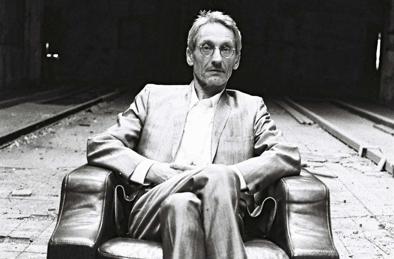 Manuel Göttsching seated and wearing a suit